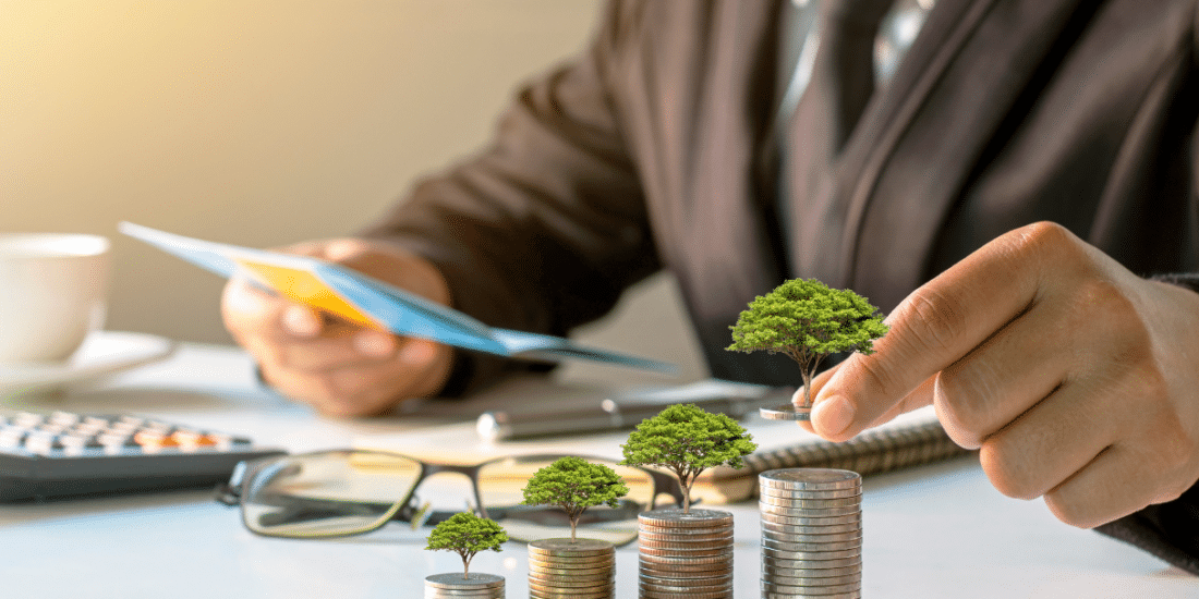 Financial person at desk with a stack of quarters with little trees on them showing growth,