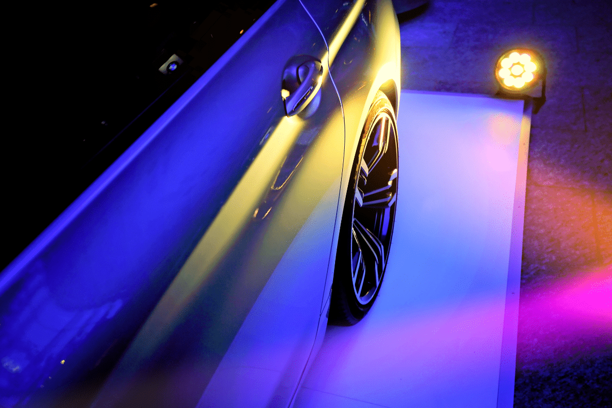 Side door and wheel of luxury car with blue and purple lights - social media marketing & luxury car dealerships